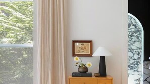 Une pièce avec un meuble en bois, un tableau encadré, un vase de fleurs et une lampe.