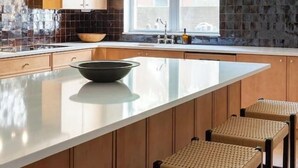 Une cuisine moderne dotée d’un grand îlot central, de meubles en bois et d’un luminaire suspendu.