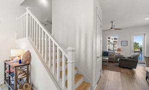 Un amplio espacio de sala con una escalera, un conjunto de sofás y una mesa de comedor.