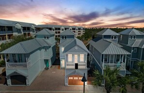 Uma área residencial costeira com várias casas de dois andares, com telhados empena e varandas frontais.