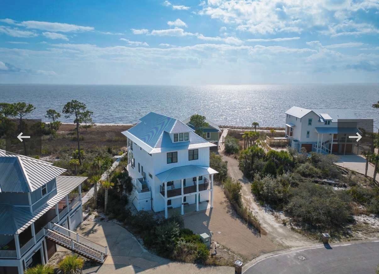 Une propriété située sur la côte, comprenant une grande maison dotée d’un balcon et d’une dépendance plus petite attenante.