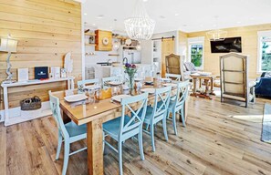 Una cocina amplia con suelo de madera, un comedor con sillas azules y una araña.