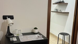 A compact workspace with a desk, a lamp, a printer, and a trash bin.