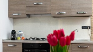 A modern kitchen with wooden cabinets, a gas stove, a coffee maker, and a vase of red tulips.
