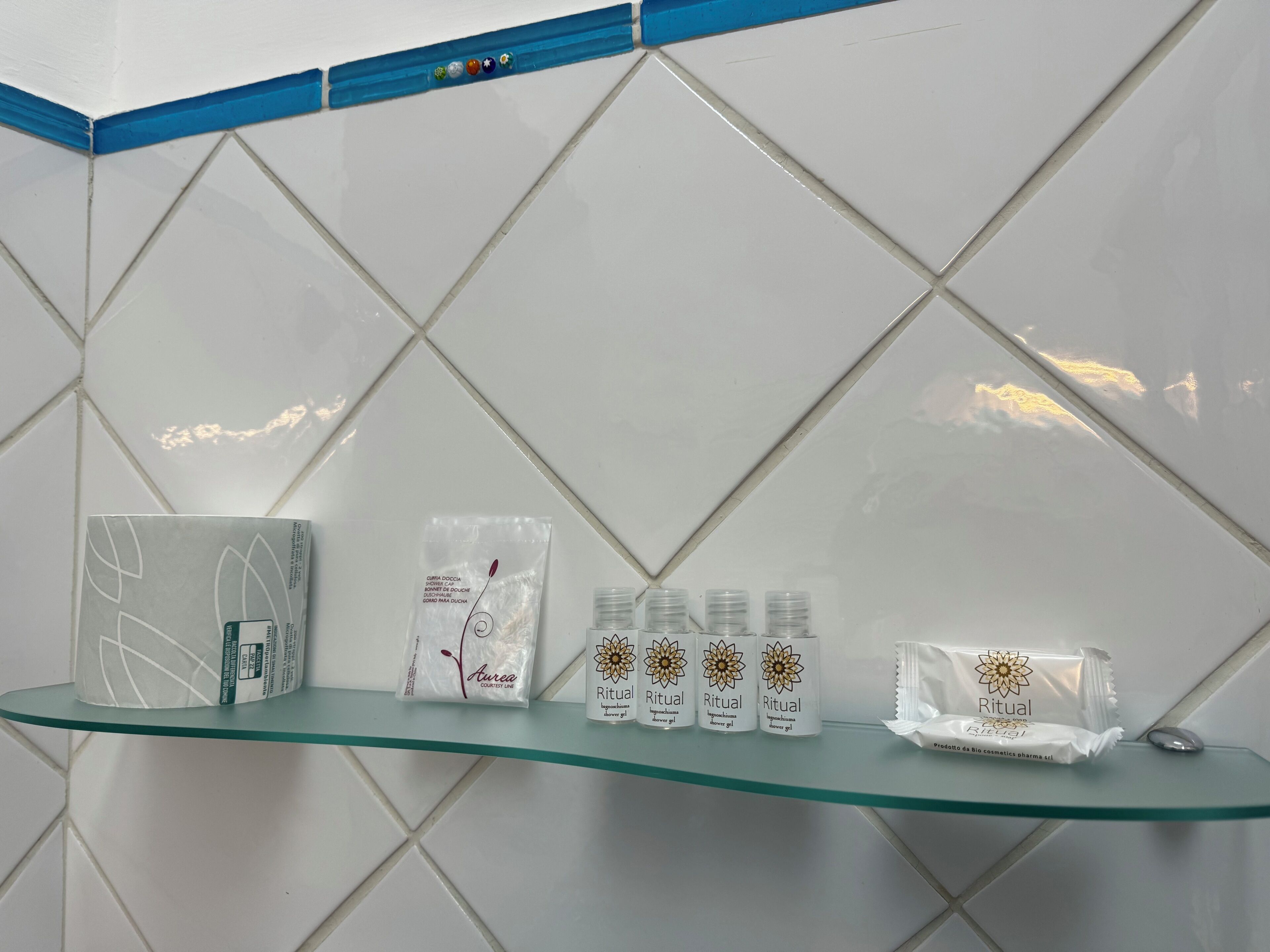 A bathroom with a glass shelf holding various toiletries.