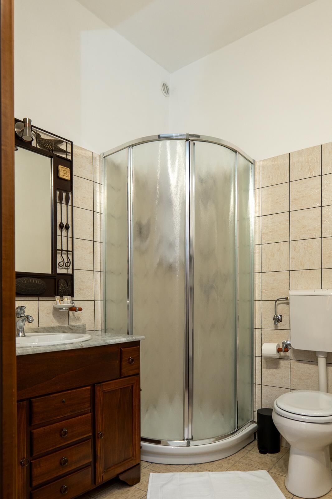 Une salle de bain avec une douche à parois de verre, un meuble-lavabo en bois et des toilettes.