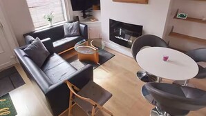 Una sala de estar con un sofá negro, una mesa de centro y una mesa redonda con sillas.