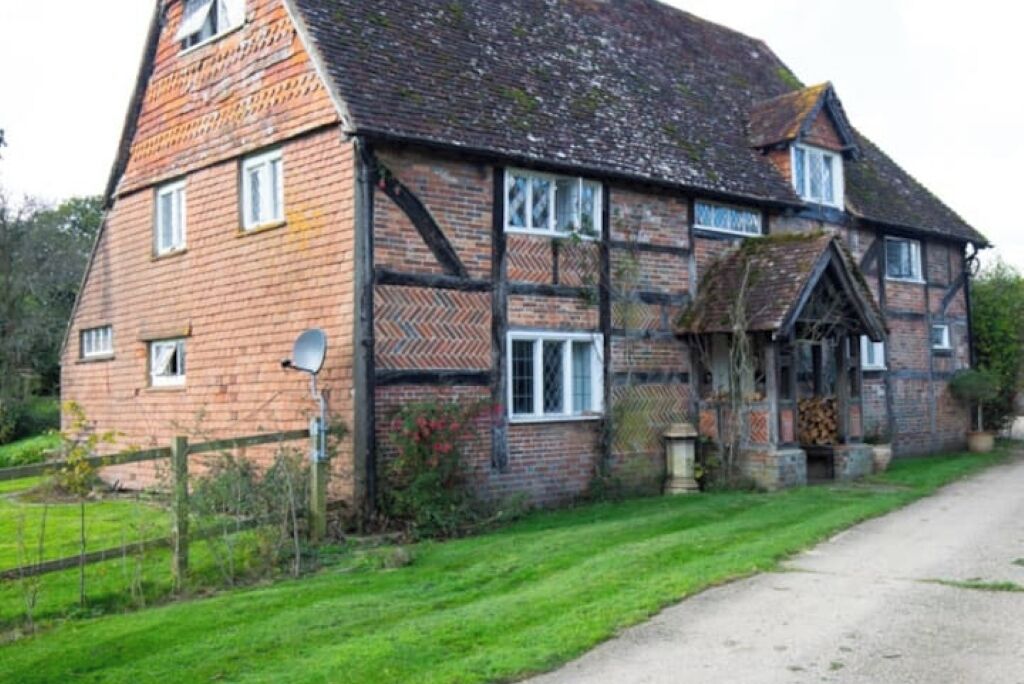 A traditional half-timbered house with a brick facade, multiple windows, and a front porch.