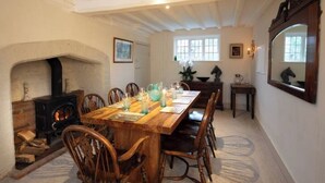 A dining room with a wooden table and chairs, a fireplace, and a large mirror on the wall. - Grade 2 Listed Rural Farm House (Chiddingfold)