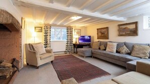 A cozy living room with a fireplace, a television, and a sofa. - Grade 2 Listed Rural Farm House (Chiddingfold)