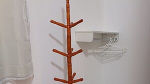 A tall, wooden coat rack with multiple hooks, positioned next to a white wall and a white tiled floor. - Eco Sítio o Labirinto do Fauno (Belem)