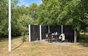Ein Terrassenbereich mit Tisch, Stühlen, einem Grill und einer Umzäunung.