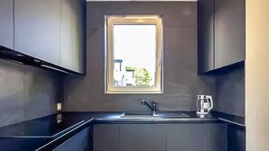 A modern kitchen with dark cabinetry, a window, a sink, and a kettle. - 1 bedroom cozy apartment in Trzesacz (Trzesacz)
