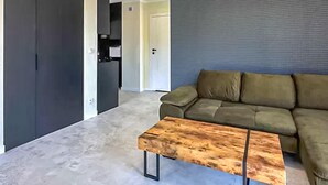 A living room with a wooden coffee table, a green sofa, and a grey textured wall. - 1 bedroom cozy apartment in Trzesacz (Trzesacz)