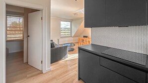 A modern kitchen with black cabinets, a hexagonal backsplash, and a dining area with a table and chairs. - Awesome apartment in Trzesacz with swimming pool (Trzesacz)