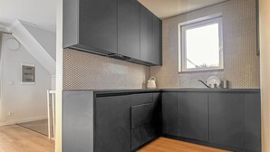 A modern kitchen with dark cabinetry, a hexagonal patterned backsplash, and a window above the sink. - Awesome apartment in Trzesacz with swimming pool (Trzesacz)