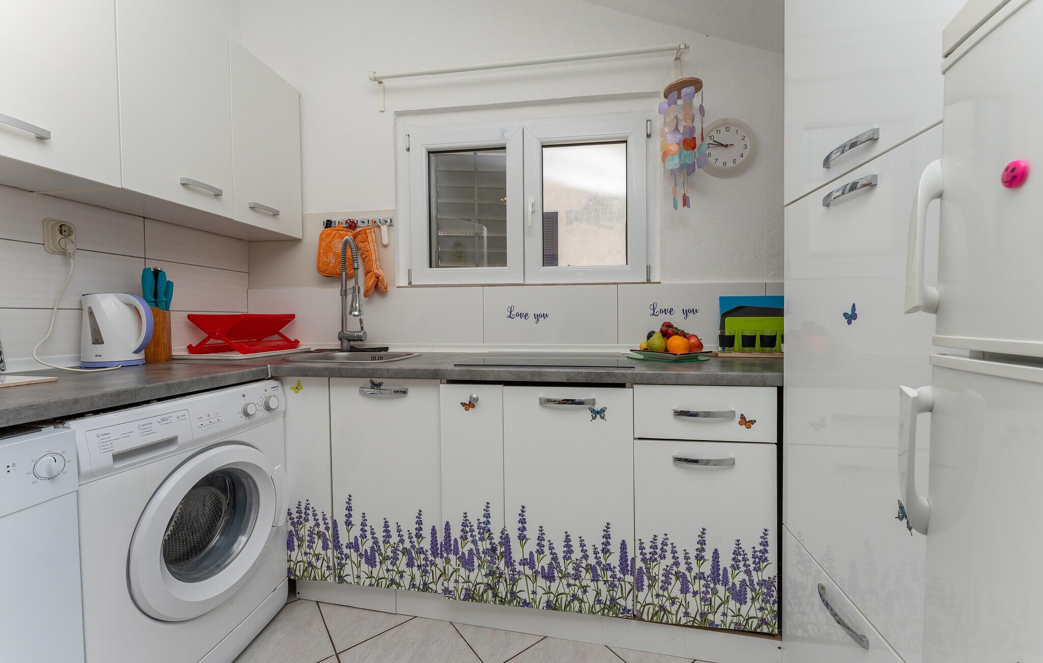 A compact kitchen with a washing machine, a sink, and a window above the countertop.