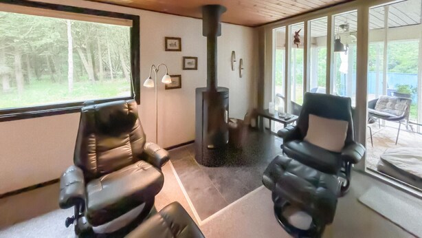 A room with two leather chairs, a fireplace, and large windows offering a view of the outdoors.
