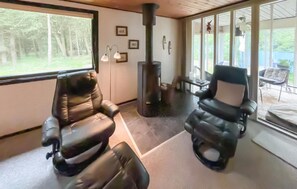 A room with two leather chairs, a fireplace, and large windows offering a view of the outdoors. - Gorgeous home in Nørre Nebel with sauna (Nørre Nebel)