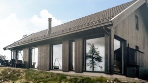 En moderne bygning med skråtag, store vinduer og skorsten.