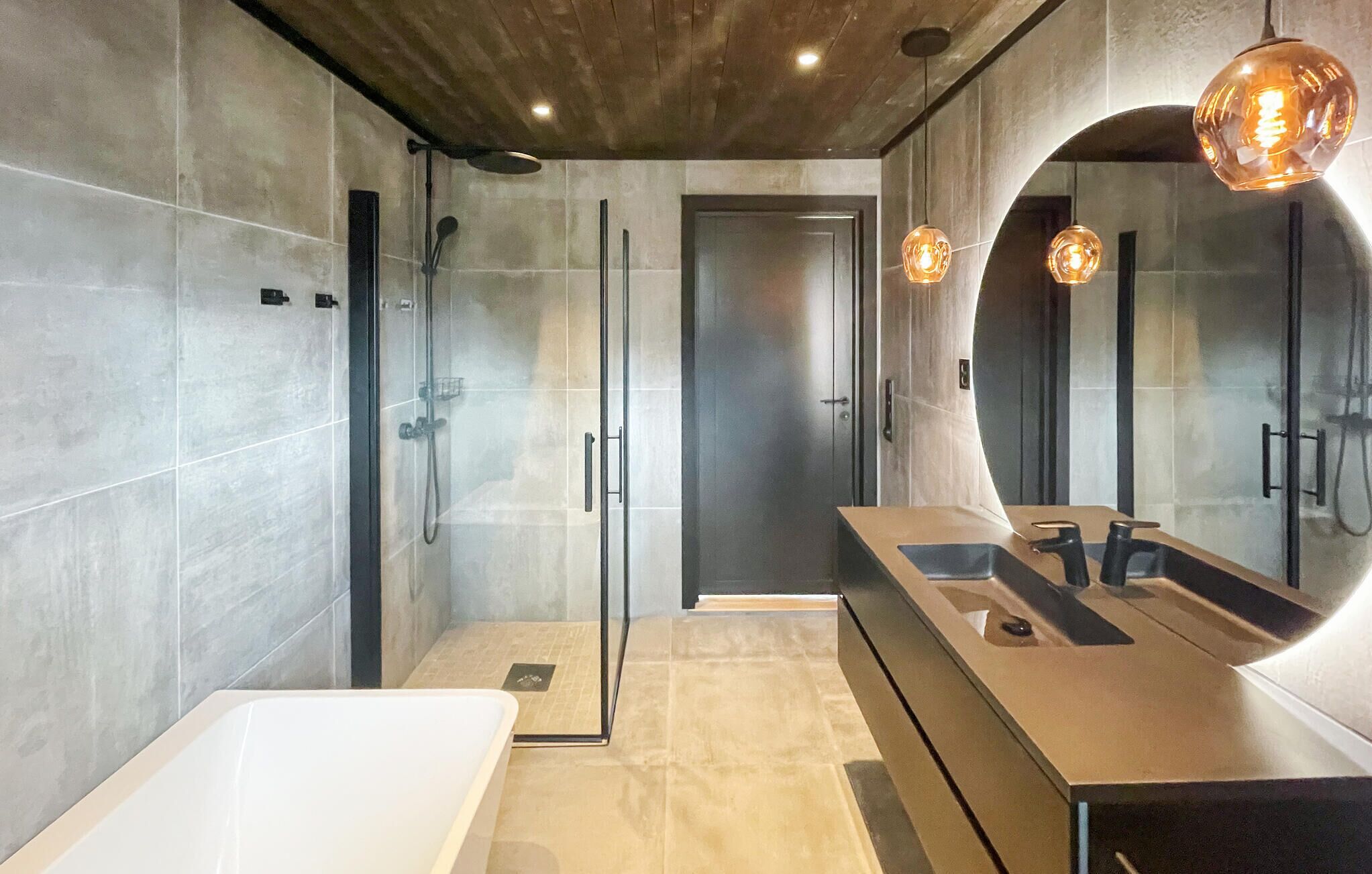 Une salle de bain moderne avec une douche à l’italienne, un grand miroir et une baignoire.