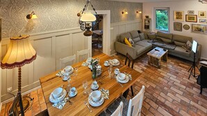 A dining area with a wooden table set for a meal, a sofa, and a lamp.