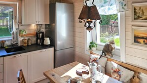 A cozy kitchen with wooden cabinets, a stainless steel refrigerator, a coffee maker, and a table set for tea.