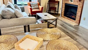 Una sala de estar con sofá, sillón, mesa de centro y chimenea.