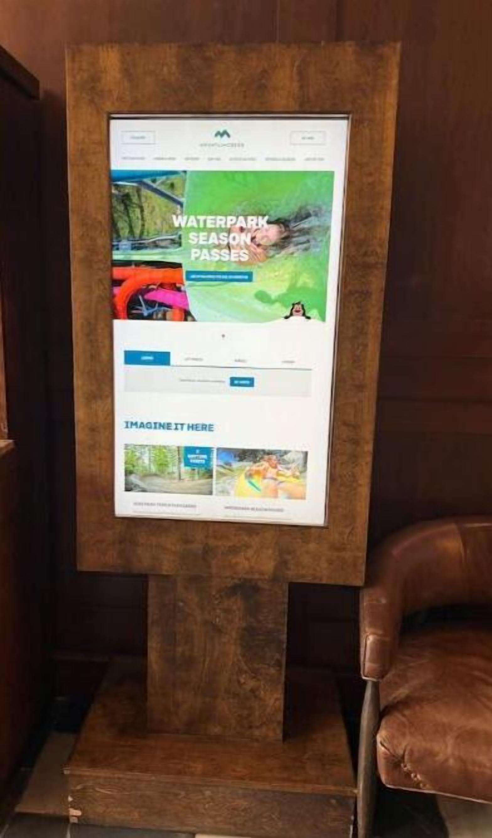 Un kiosque numérique doté d’un écran affichant une publicité pour les abonnements saisonniers d’un parc aquatique.