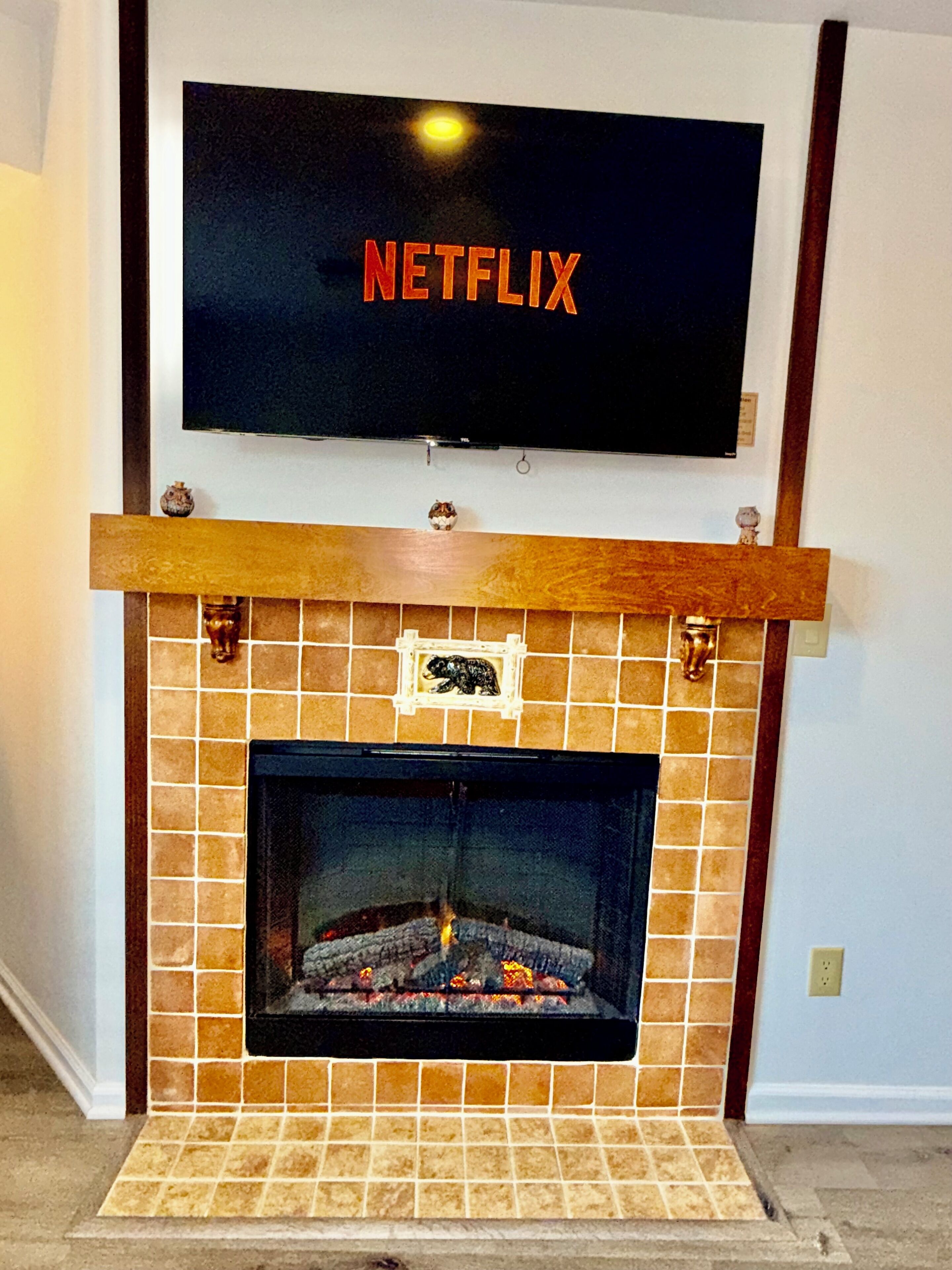 Een open haard met erboven een televisie waarop het Netflix-logo te zien is.