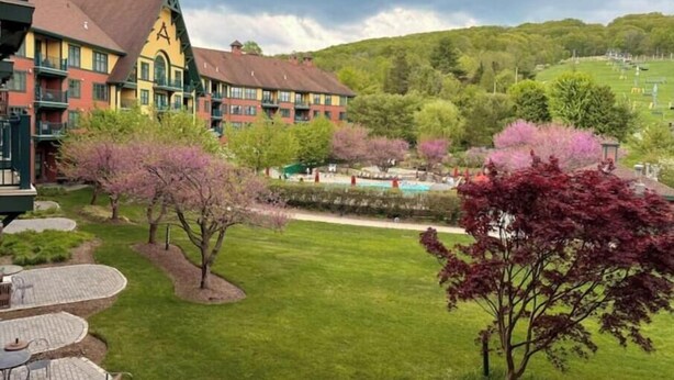 Un hotel con césped verde, mobiliario exterior y una zona de piscina.