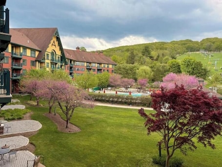 A hotel with a green lawn, outdoor seating, and a pool area.