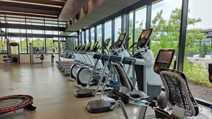 A gym with treadmills aligned in rows, large windows, and a view of greenery outside. - Cozy Apartment in Austin by The Key Rentals (Austin)