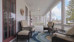 Une véranda avec des fauteuils en osier et un tapis à motifs bleus.