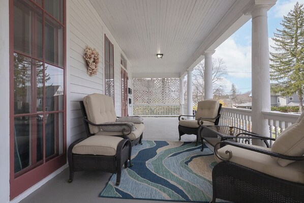 A covered porch with wicker chairs and a blue patterned rug. - La Victoria 5-bedroom estate in the heart of Warwick, an Hour away from NYC (Warwick)
