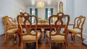 Une salle à manger élégante, avec une table et des chaises en bois, un lustre et un grand miroir.