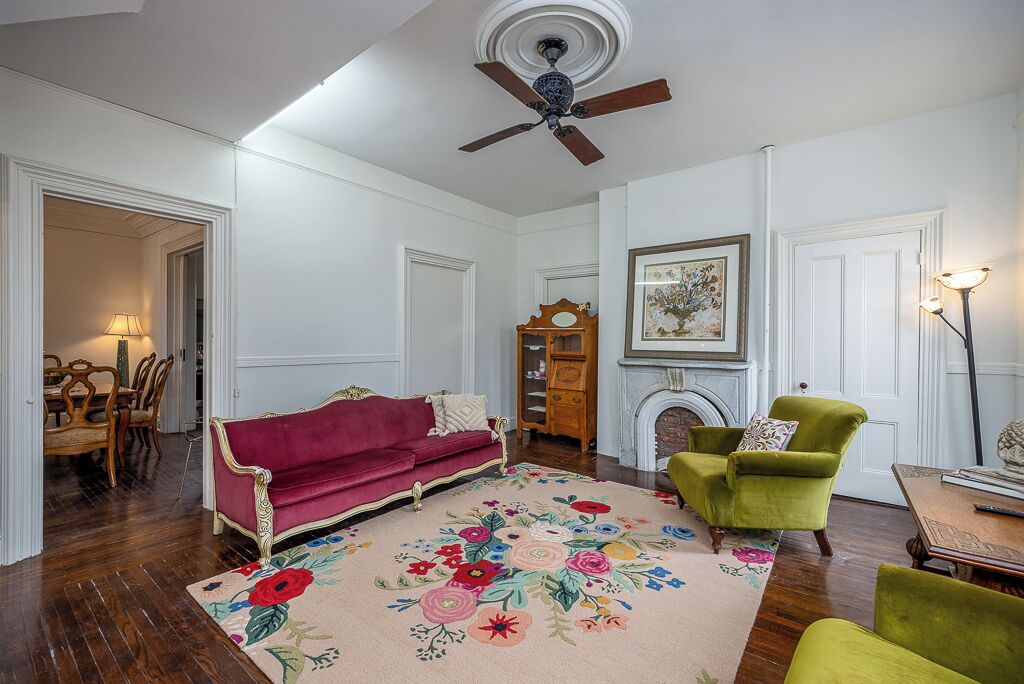 Ein Wohnzimmer mit einem roten Sofa, einem grünen Sessel und einem floralen Teppich.