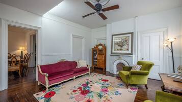 Ein Wohnzimmer mit einem roten Sofa, einem grünen Sessel und einem floralen Teppich.