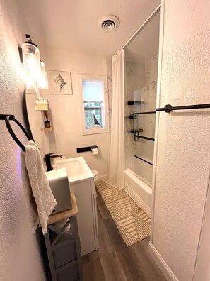 Ein kleines Badezimmer mit Dusche, einem kleinen Fenster und einem Handtuchhalter.