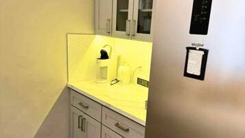 A compact kitchen with a stainless steel refrigerator, a yellow countertop, and grey cabinets.