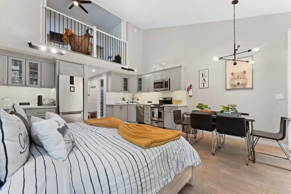 A modern apartment with a loft bedroom, a dining area, and a kitchen.