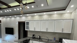 A modern kitchen with white cabinetry, a granite countertop, a built-in microwave, and a refrigerator.