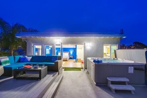 Een moderne buitenruimte met een jacuzzi, een bank en een eettafel.