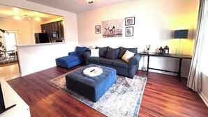 A living room with a sectional sofa, ottoman, and a ceiling fan. - 2-bedroom townhome in enjoyable Charlotte with WiFi, AC (Charlotte)