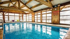 Una piscina interior con vigas de madera y ventanas amplias.