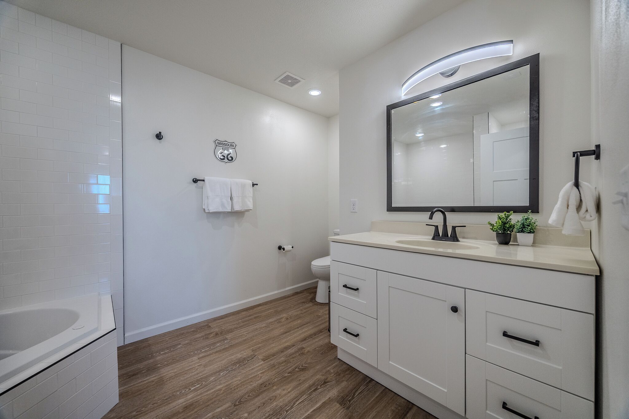 A modern bathroom with a white vanity, a large mirror, and a shower area.