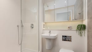 Ein modernes Badezimmer mit Duschkabine aus Glas, einem Standwaschbecken und einer Toilette.