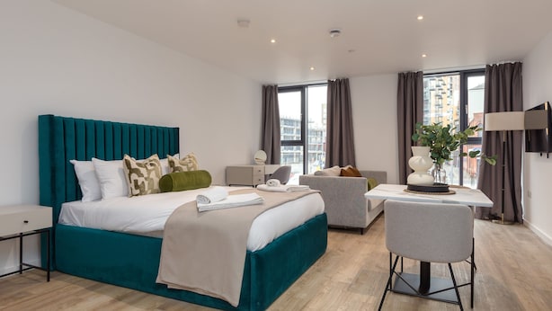 Et moderne hotelværelse med en stor seng, et skrivebord og en stol.