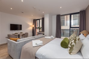 Una habitación de hotel moderna con una cama grande, un sofá, un escritorio y una televisión.