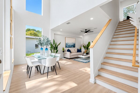 A modern interior with a dining area, living room, and staircase.
